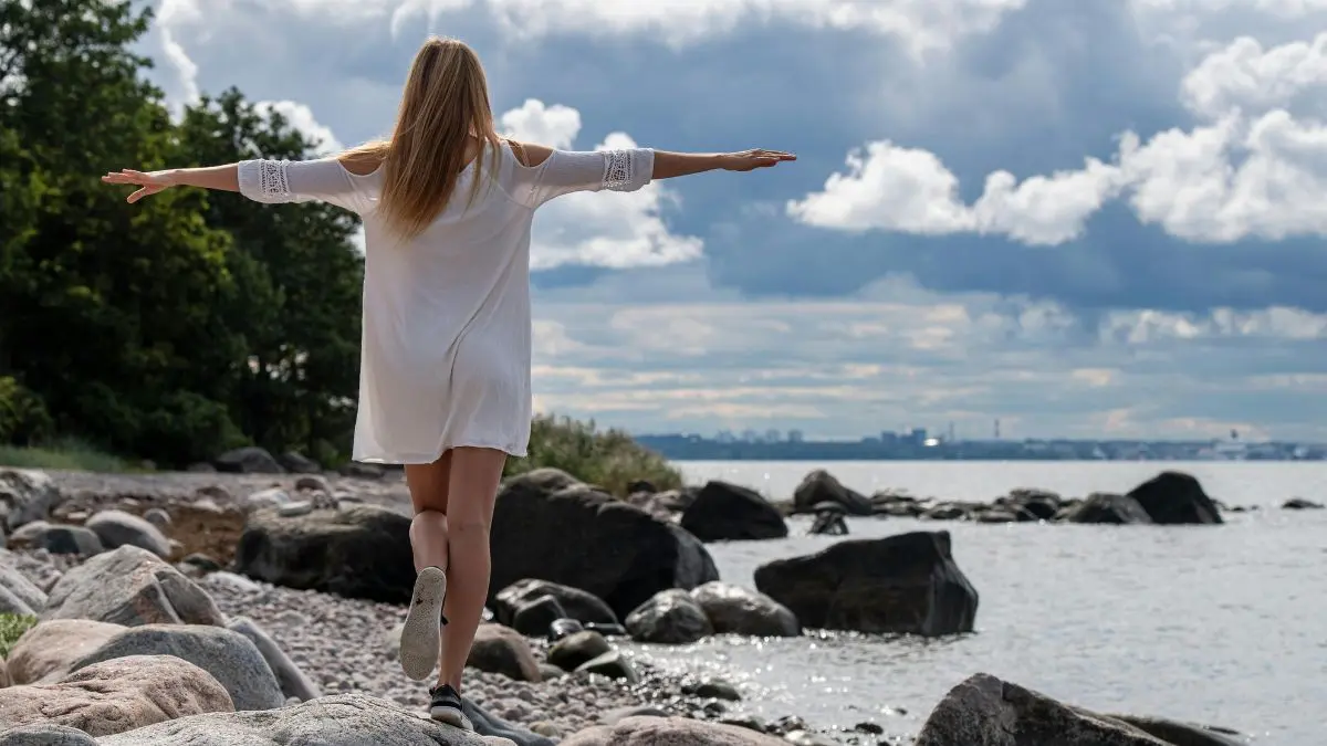 Frau in Balance an einem See - Sinnbild für gesundheitliche Selbstermächtigung